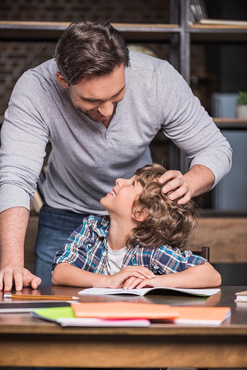 young father helping little smiling son with homework