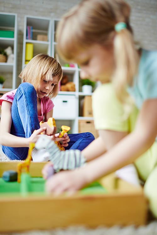 Little girls playing with toys in kindergarten